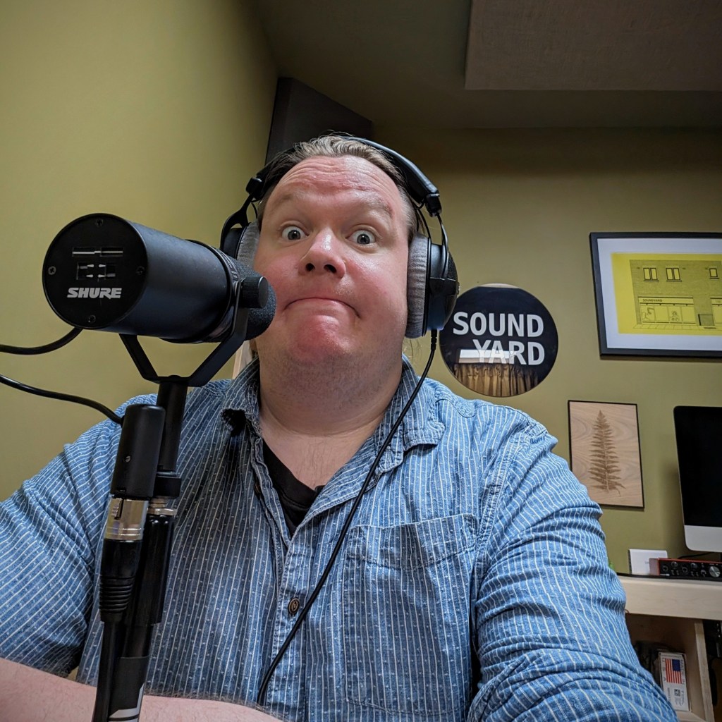 Man wearing headphones, sat in front of a microphone in a podcast studio