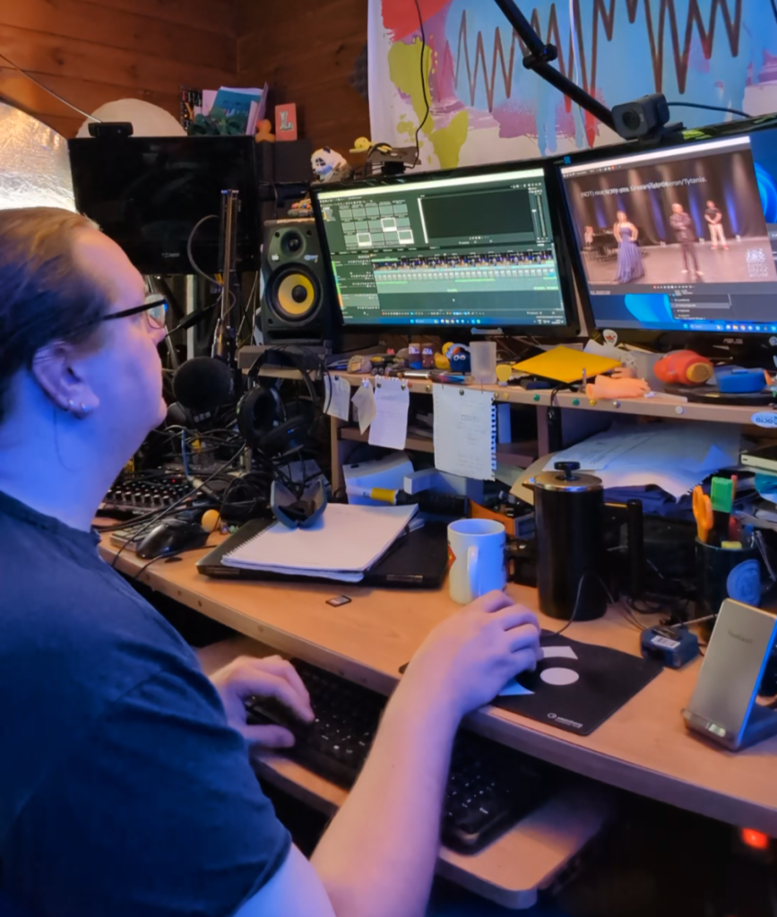 Man with glasses edits video on a PC